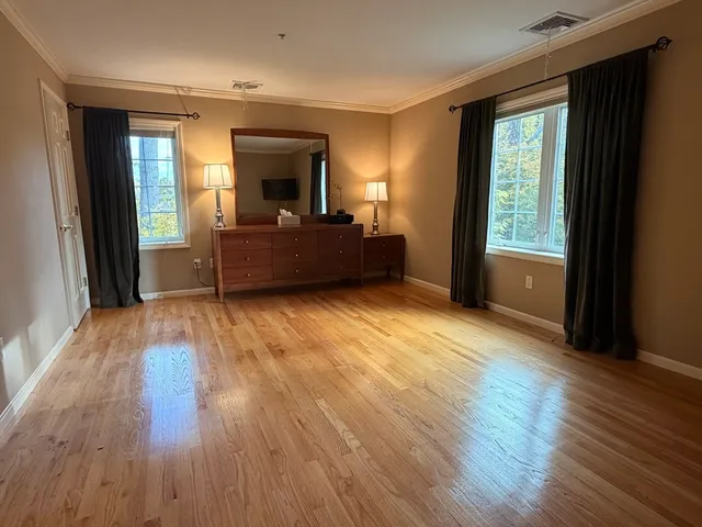 a view of empty room with wooden floor and fan
