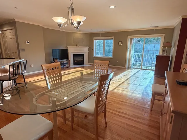 a kitchen with stainless steel appliances granite countertop a kitchen island a stove a refrigerator a sink a dining table and chairs with wooden floor