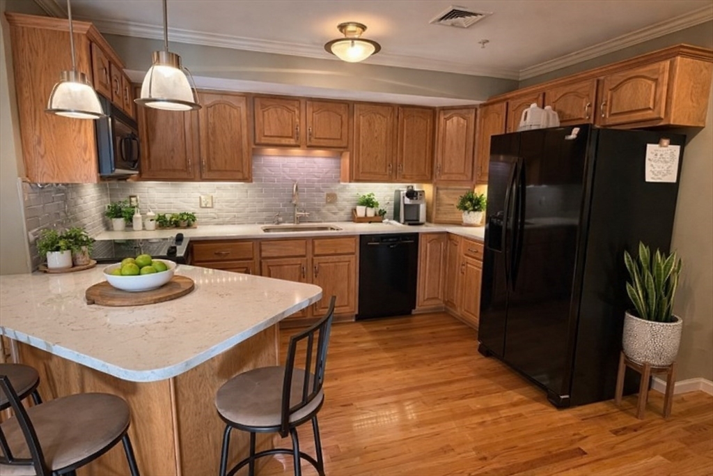 7 Conant Road, Unit 21 Winchester, MA 01890 - Photo 5 of 27 a kitchen with stainless steel appliances granite countertop a kitchen island a stove a refrigerator a sink a dining table and chairs with wooden floor