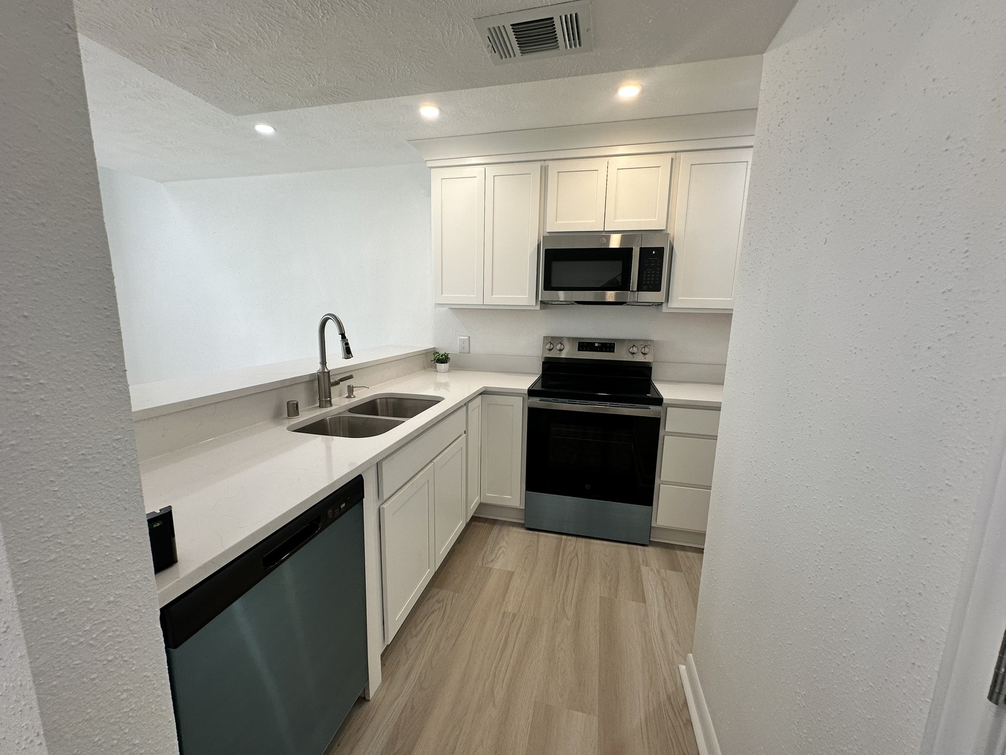 2800 Jeanetta Street, Unit 203 Houston, TX 77063 - Photo 9 of 34 a kitchen with a sink dishwasher a stove top oven a refrigerator with wooden floor and cabinets