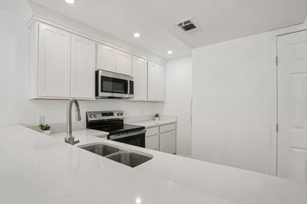 a kitchen with granite countertop white cabinets and black stainless steel appliances