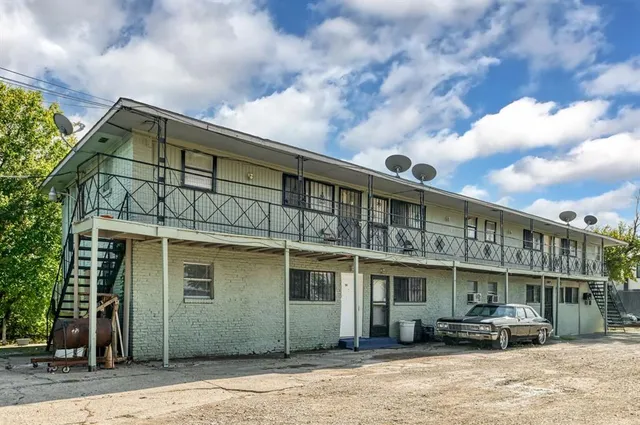 a front view of a building with lot of cars and trees