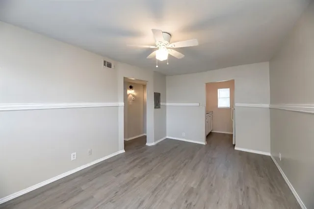 an empty room with wooden floor closet ceiling fan and windows