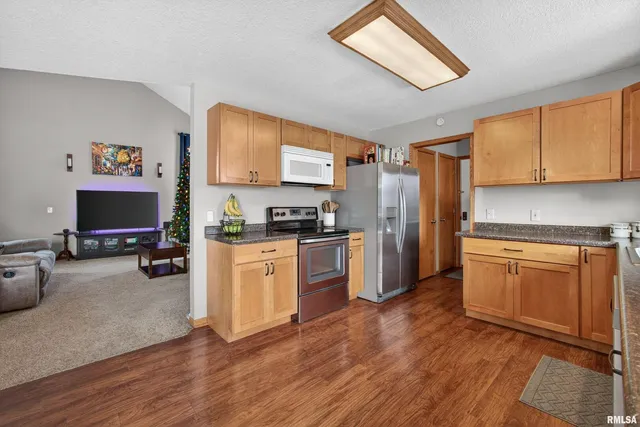 a kitchen with granite countertop a refrigerator stove top oven and sink