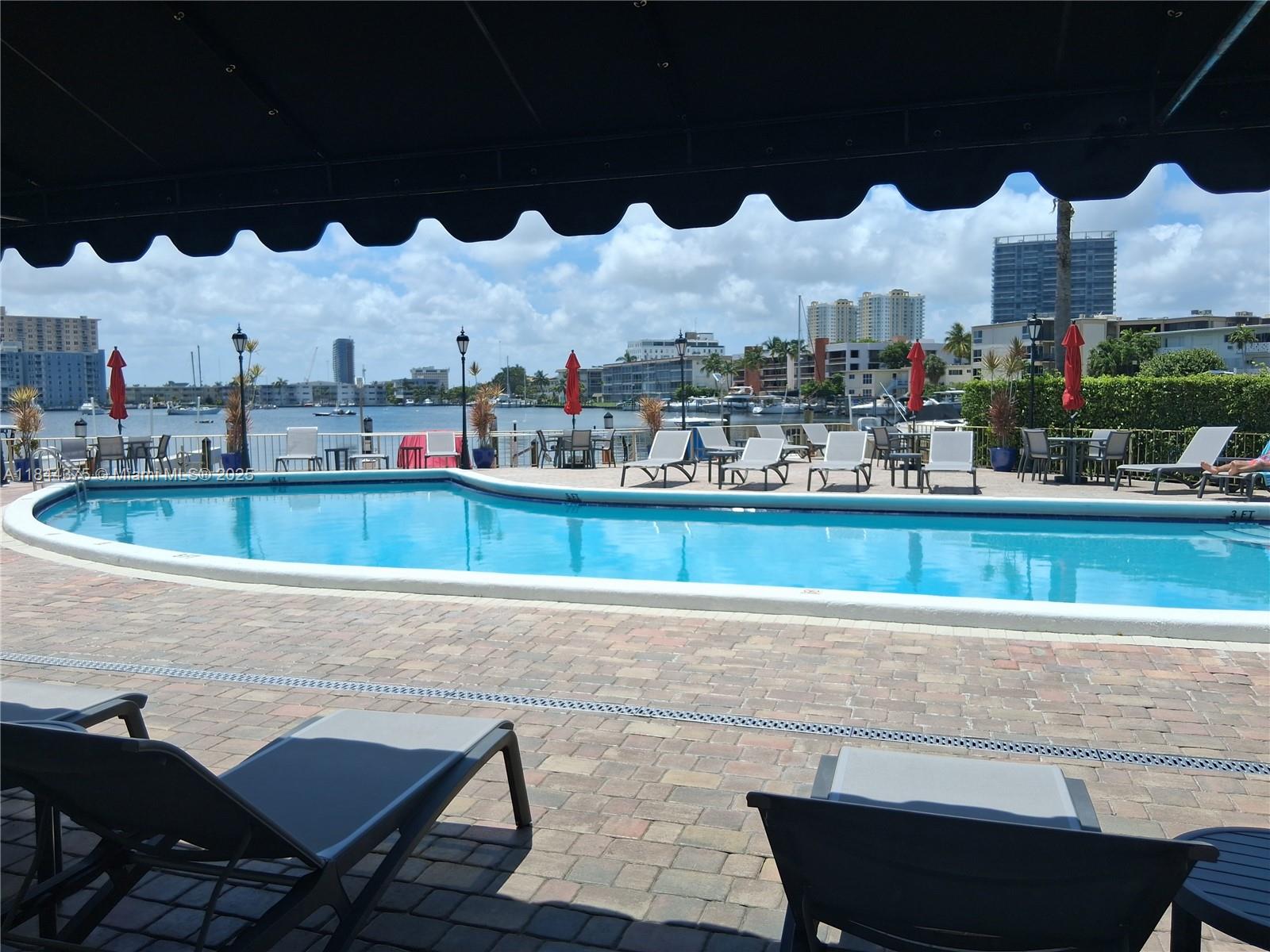 100 Golden Isles Drive, Unit 206 Hallandale Beach, FL 33009 - Photo 12 of 22 a view of swimming pool with outdoor seating and buildings in the background