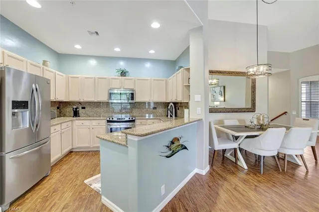 a kitchen with kitchen island stainless steel appliances a dining table and chairs