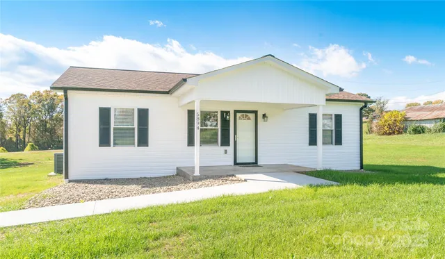 a view of a yard in front of a house with large windows