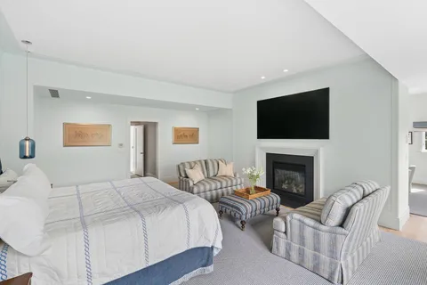 a bedroom with bed a flat screen tv and a fireplace