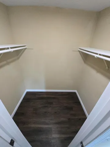 an empty room with wooden floor chandelier fan and windows