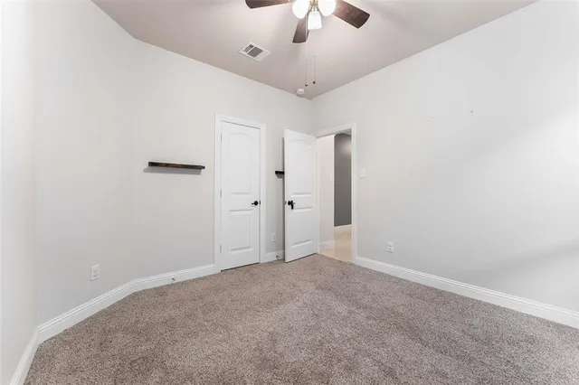 an empty room with a ceiling fan and a window