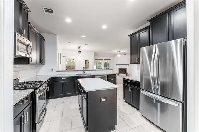 a kitchen with stainless steel appliances granite countertop a refrigerator a sink a stove and oven