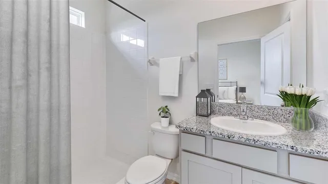 a bathroom with a granite countertop sink a toilet and mirror