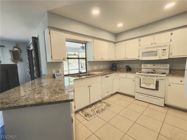 a kitchen with kitchen island granite countertop a sink window and cabinets