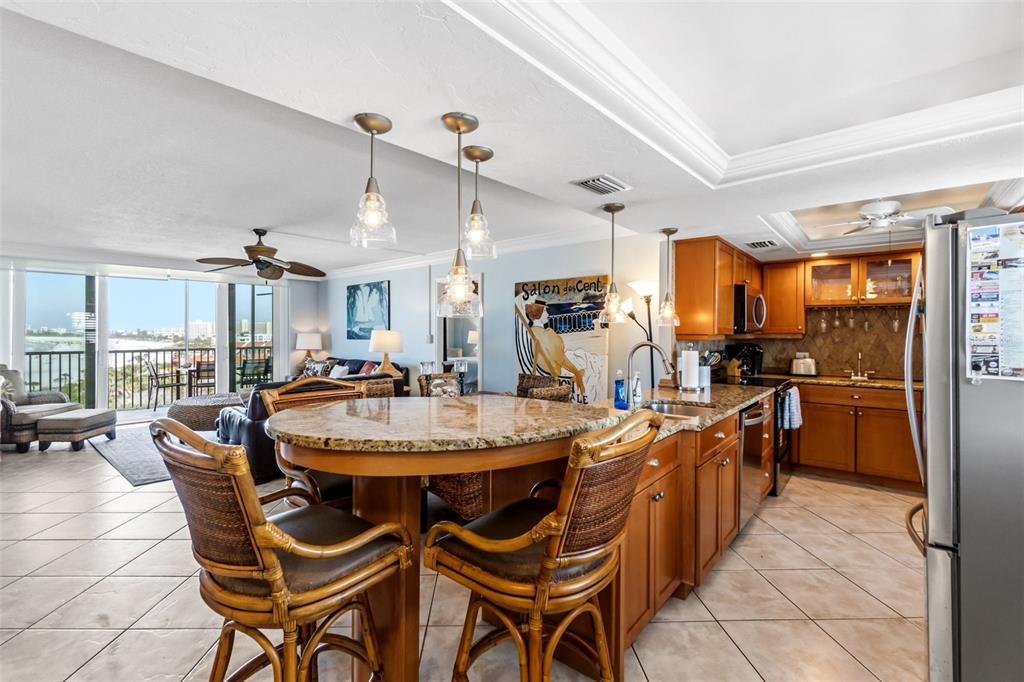 6300 Midnight Pass Road, Unit 708 Sarasota, FL 34242 - Photo 5 of 49 a dining hall with stainless steel appliances kitchen island granite countertop a table chairs and a refrigerator