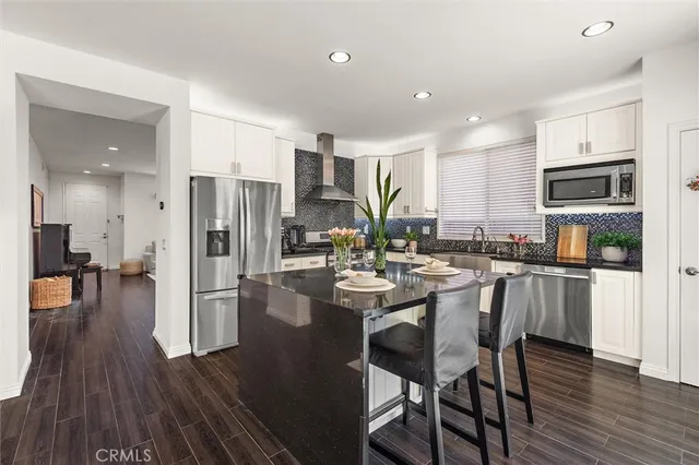 a kitchen with a sink a refrigerator a stove and chairs with wooden floor