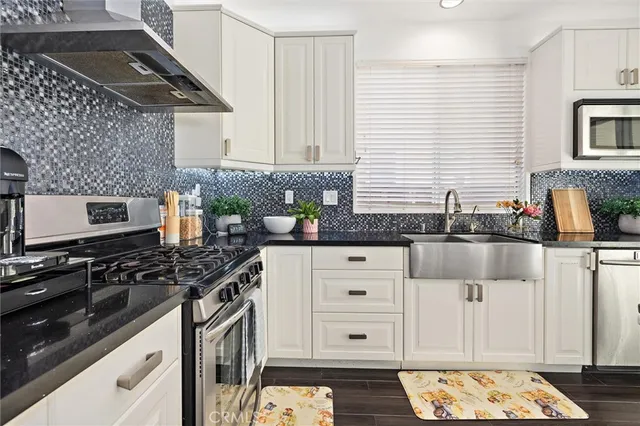 a kitchen with granite countertop a stove a sink and white cabinets