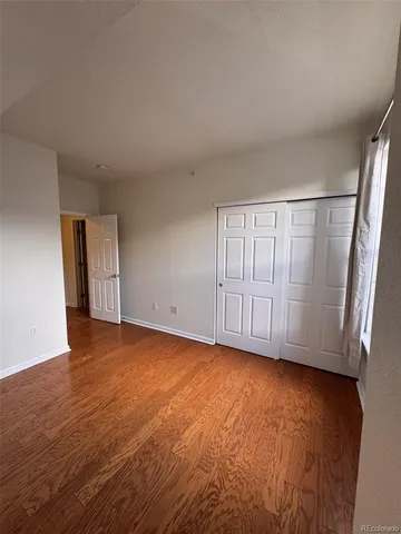 a view of an empty room with wooden floor and closet