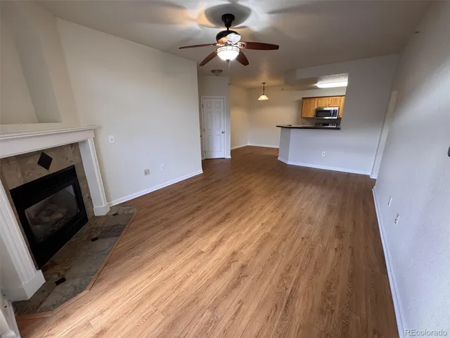 a view of an empty room with wooden floor and a fireplace