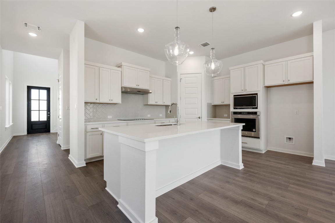 a kitchen with stainless steel appliances kitchen island wooden floors and white cabinets
