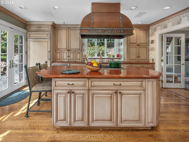 a kitchen with stainless steel appliances granite countertop a stove a sink and a dining table with wooden floor