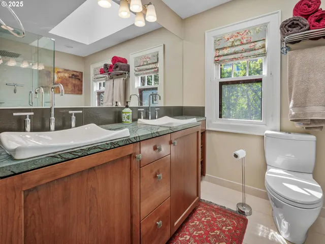 a en suite bathroom with a granite countertop toilet a sink and a window