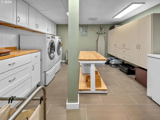 a view of a white house next to a yard with big trees