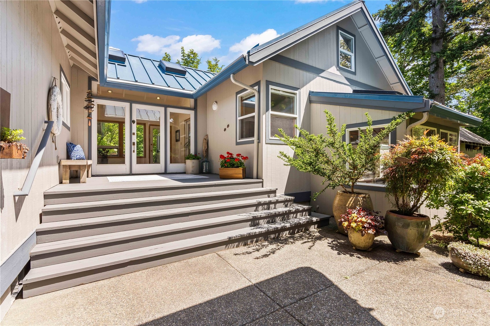 8615 Higgins Cove Road Anderson Island, WA 98303 - Photo 7 of 40 a view of a house with potted plants and a bench