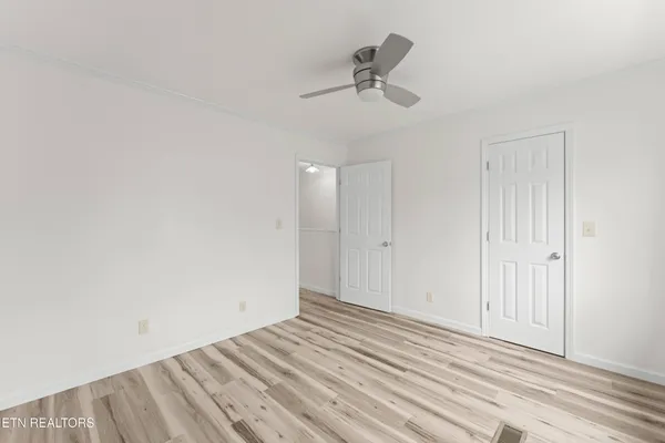 a view of empty room with wooden floor and fan
