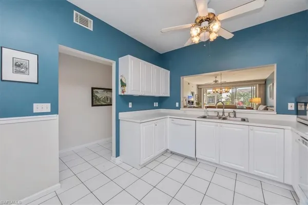 a kitchen with white cabinets and chandelier