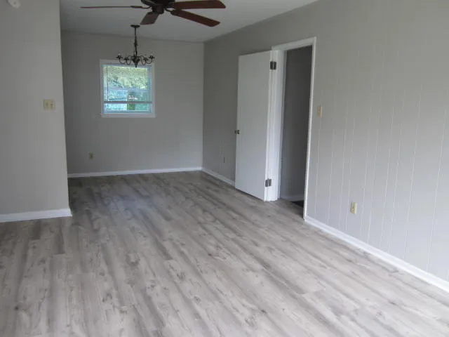 an empty room with wooden floor and ceiling fan