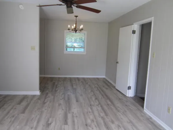 an empty room with wooden floor chandelier and closet