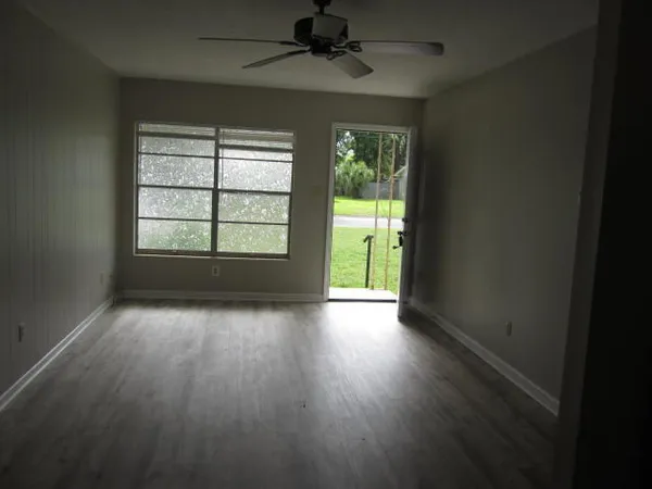 an empty room with wooden floor and windows