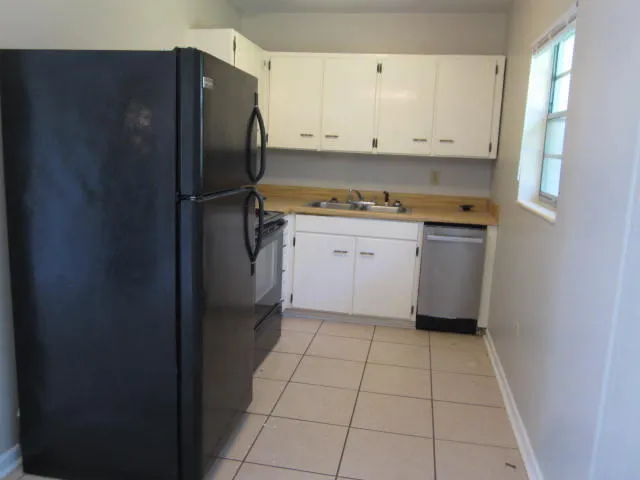 a kitchen with white cabinets and refrigerator