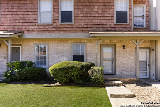 a view of brick house with a yard
