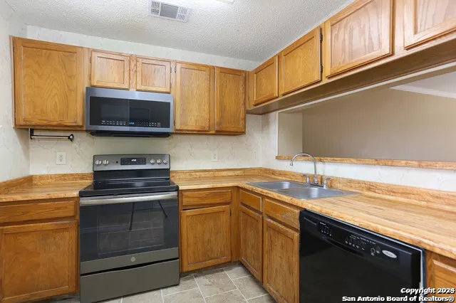 a kitchen with stainless steel appliances granite countertop a sink stove microwave and refrigerator