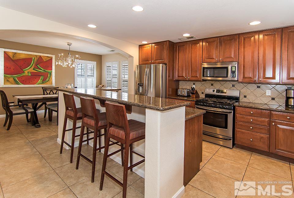 7676 Pebblestone Way Reno, NV 89523 - Photo 8 of 20 a kitchen with stainless steel appliances granite countertop wooden cabinets a stove a sink a dining table and chairs