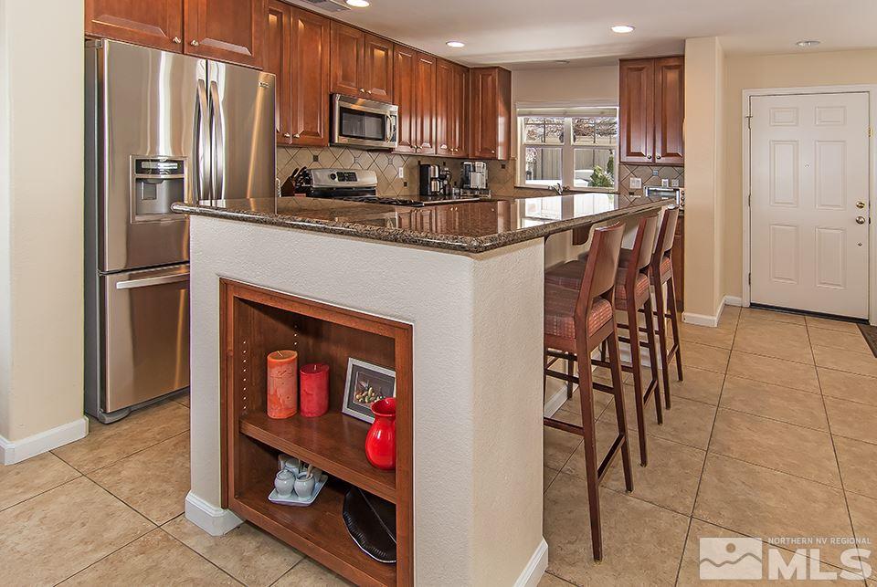 7676 Pebblestone Way Reno, NV 89523 - Photo 9 of 20 a kitchen with stainless steel appliances granite countertop a refrigerator and a stove top oven