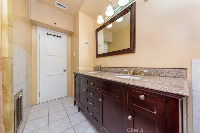 a bathroom with a granite countertop double vanity sink and mirror