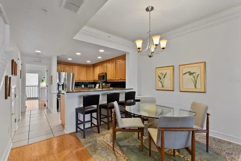 a dining room with wooden floor a chandelier a glass table and chairs