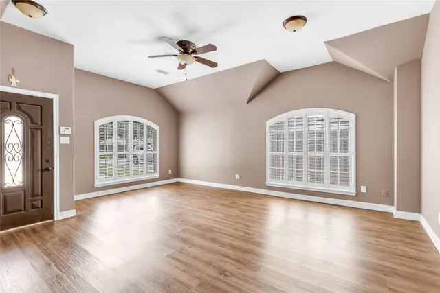 a view of an empty room with wooden floor and a window