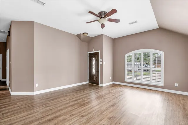 an empty room with wooden floor and windows