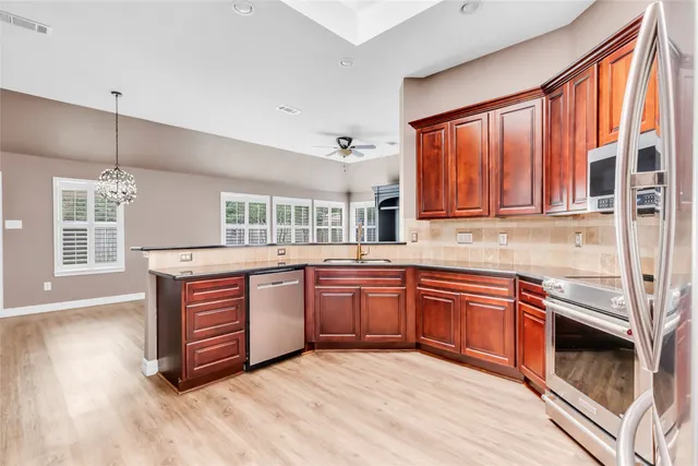 a kitchen with stainless steel appliances granite countertop a stove a sink dishwasher and a microwave oven with wooden floor