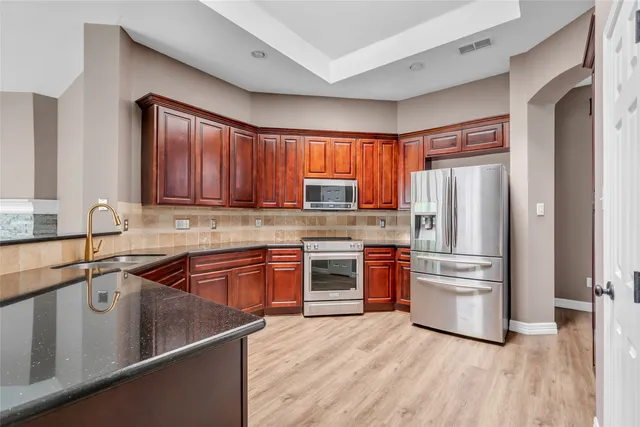 a kitchen with stainless steel appliances granite countertop a refrigerator stove and sink