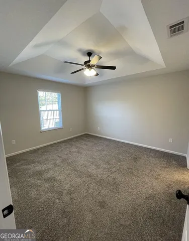 an empty room with windows and ceiling fan