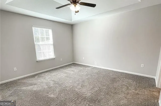 an empty room with a window and a ceiling fan