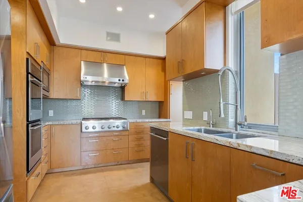 a kitchen with stainless steel appliances granite countertop a refrigerator and a sink