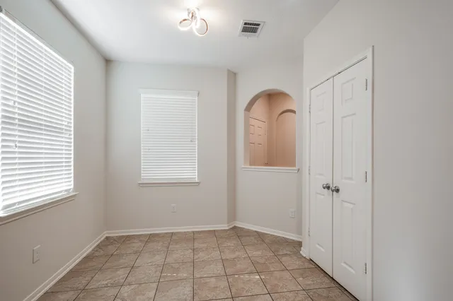 a view of an empty room with window and chandelier fan
