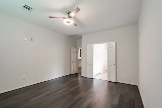 an empty room with wooden floor and ceiling fan