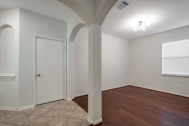 an empty room with wooden floor cabinet and windows