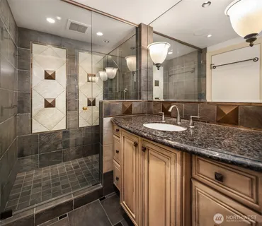 a bathroom with a granite countertop sink a mirror and shower